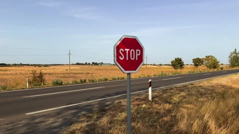 STOP traffic sign prominently standing along an empty rural highway. Concep.. Stock Footage 346400572