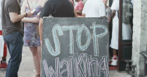 "Stop Walking Start Drinking" sign on sidewalk at SXSW Festival 4K Video stock 22845544