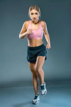 Stopped motion front view of focused female athlete running to the camera. Fu Stock Photos