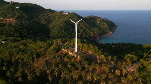 Stopped single wind turbine on a hill among palm trees on seascape background Stock Footage 244069155