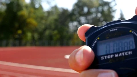 Stopwatch in hand and blurred female runner athlete on stadium Stock Footage