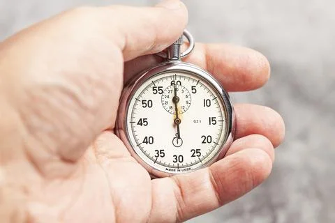 Stopwatch in hand on a gray background Stock Photos