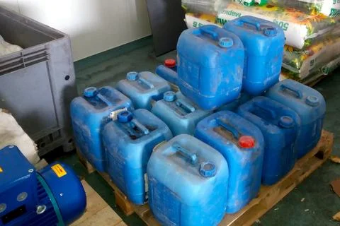 Storage Area Containing Blue Canisters Stacked on Wooden Pallets Near Equip.. Stock Photos