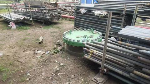 A storage area featuring stacked pipes and a circular green platform. Photos