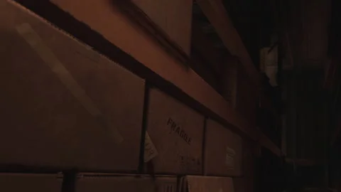 Storage area with stacked boxes and shelves in a dark room Stock Footage 345044728