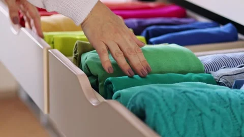 Storage concept. Women's hands carefully take a bright T-shirt from a wardrobe Stock Footage 250935793