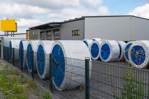 Storage facility with large blue-covered coils surrounded by fencing Stock Photos