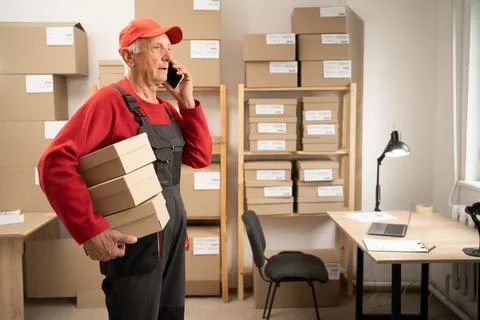 Storage with orders of online E-commerce store. Senior male warehouse talks t Stock Photos