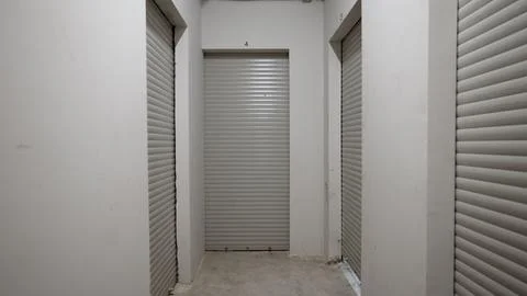 Storage unit corridor with closed roller doors and concrete floor Stock Photos