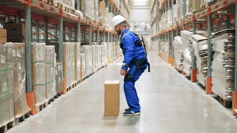 Storage worker is lifting a box while wearing ergoskeleton Stock Footage 160849983