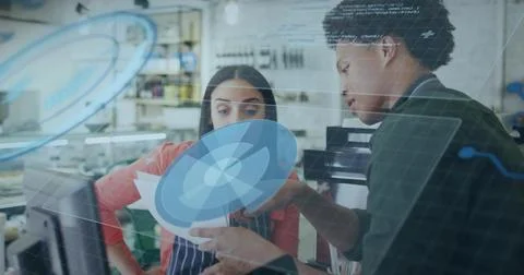 Store co-workers reviewing schematic at craft workshop, with printout, computer Foto stock