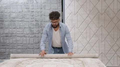 Store employee rolling an oriental carpet in a showroom Stock Footage 336965846