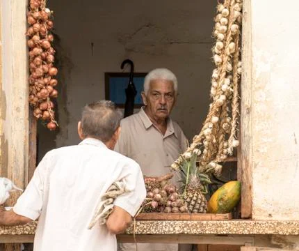 Store keeper specializing in garlic talks to customer in window Foto stock