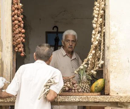 Store keeper specializing in garlic talks to customer in window Stock Photos
