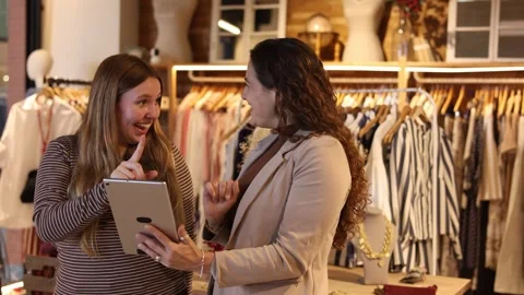 Store manager assisting customer with tablet in clothing boutique Stock Footage 344314304