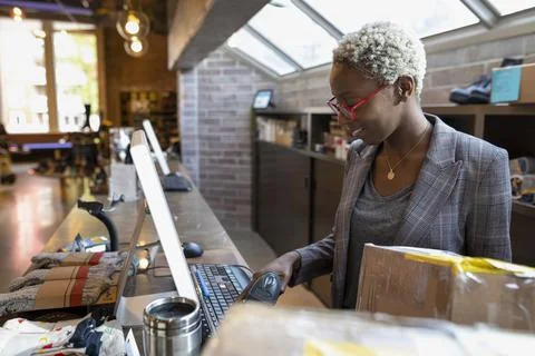 Store owner using computer and holding barcode reader Foto stock
