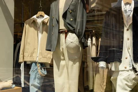 A store window shows a display of clothes including jackets, pants, and acc.. Fotos Stock