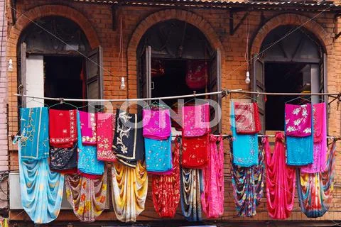 Storefront of old nepal textile shop with many multicolored garments Stock Photos