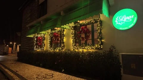 Storefront Windows Decorated with Greenery Wreaths and Warm String Lights at Nig Stock Footage 322916266