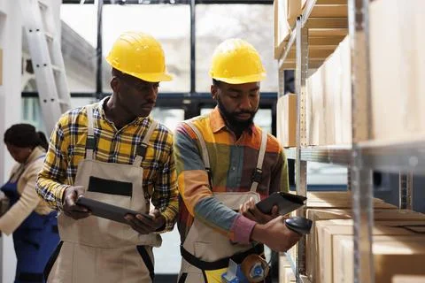 Storehouse operators checking orders in tablet and scanning parcels Stockfoto's