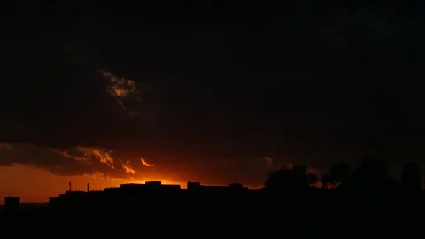 A storm cloud covers the city as the sun sinks behind the buildings Stock Footage 273588831