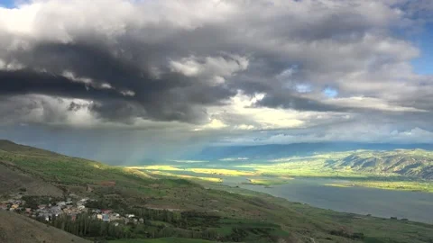 Storm clouds and heavy rain approach lake, village and farmland panorama in Vídeos de archivo 333772507