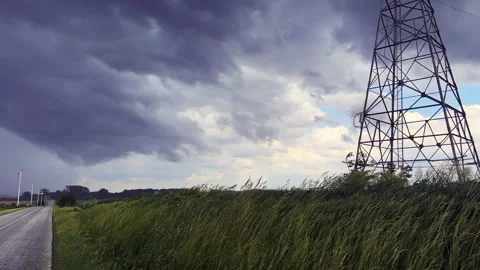 Storm clouds and high voltage transmission tower by a rural road Video stock 343561375