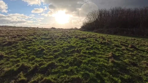 Storm clouds approaching sunrise sunlit rural grassy meadow hillside Stock Footage 325662750