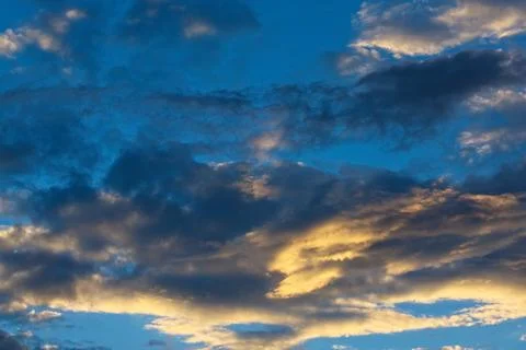 Storm clouds in a blue sky at sunset. Stock Photos