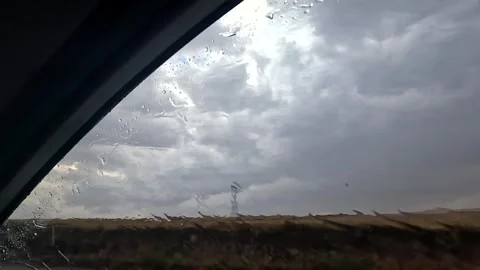 Storm clouds breaking beyond a rain-covered car window Stock Footage 343805242