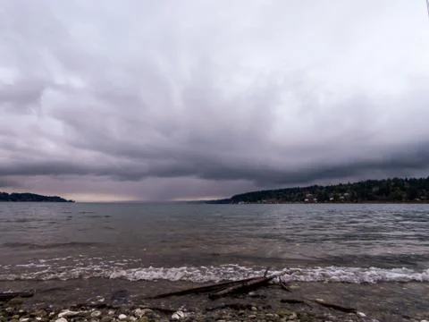 Storm clouds building over rocky pebble covered shore Stock Photos