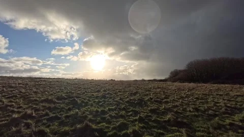 Storm clouds covering bright glowing sunrise sunlit grass meadow hillside Stock Footage 325661627