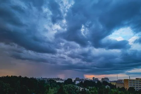 Storm clouds. Dramatic sky over city. Thunderstorm weather. Rain pours from c Stock Photos