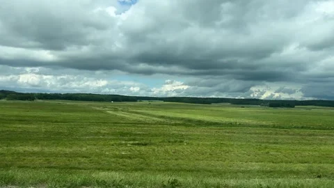 Storm clouds gather over a green meadow and forest horizon Stock Footage 337434182