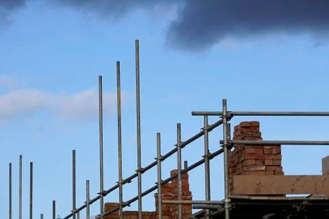 Storm clouds gathering over a building site with scaffolding and bricks piled Stock Photos