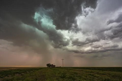 Storm clouds gathering over a small house on the horizon in a flat landscape. Stock Photos