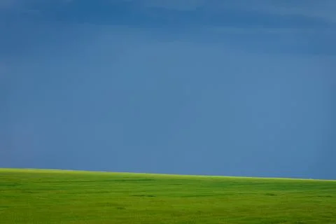 Storm clouds gathering over a wide green field, creating a dramatic natural.. Stock Photos