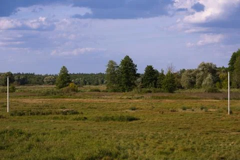 Storm clouds hung over the forest, wild field and power line. Stock Photos