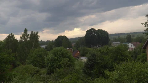 Storm clouds hung over a small village surrounded by green trees Stock Footage 136635349