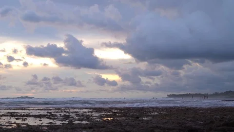 Storm clouds move in view of a sunset over a tidal beach Stock Footage 74290383