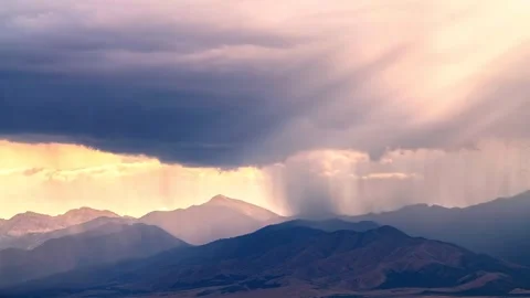 Storm clouds moving over rugged mountains at golden hour Stock Footage 341328467