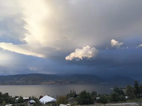 Storm clouds over lake and mountains at sunset Stock Photos