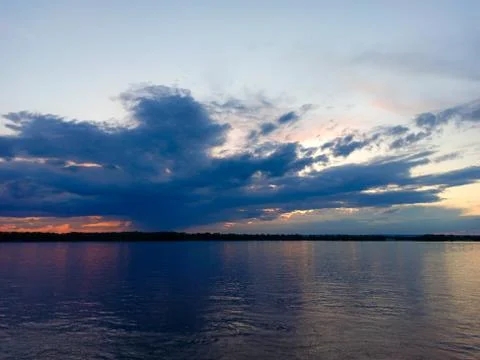 Storm clouds over the river at sunset Stock Photos