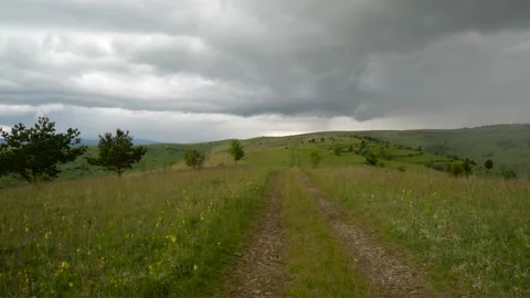 Storm clouds over a small dirt road on the top of the hill at springtime Stock Footage 131107003
