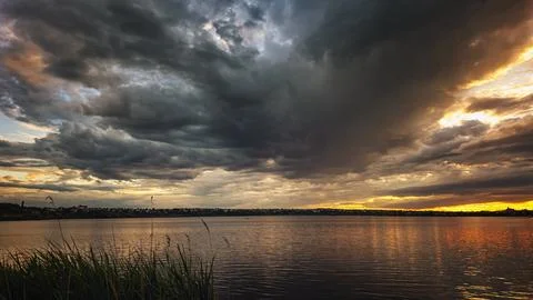 Storm clouds over sunset lake Stock Photos