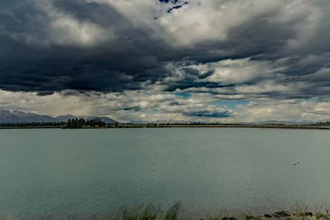 Storm Clouds Over Tranquil Lake Distant Mountains Foto stock
