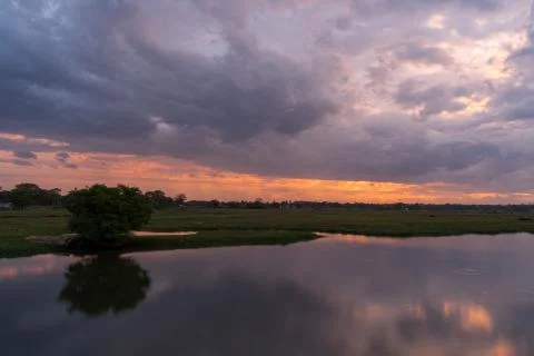 Storm clouds over the water and sunset over the lake Stock Photos