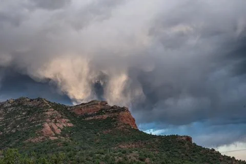 Storm clouds reflect sunlight over red rocks formation near Sedona, Arizona Stock Photos