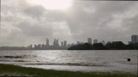 Storm clouds sweep over choppy waters of river with city outline gracing horizon Stock Footage 158967575