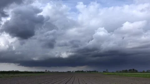Storm clouds timelapse above plowed field as tractor works on broad countryside Stock Footage 339485254